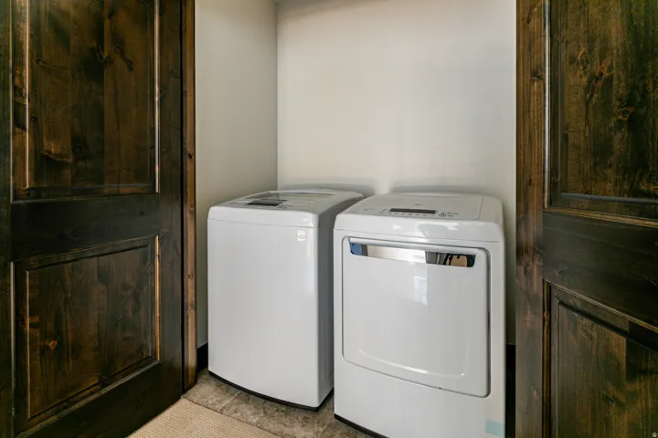Laundry area featuring white appliances and panel doors with a dark wood finish