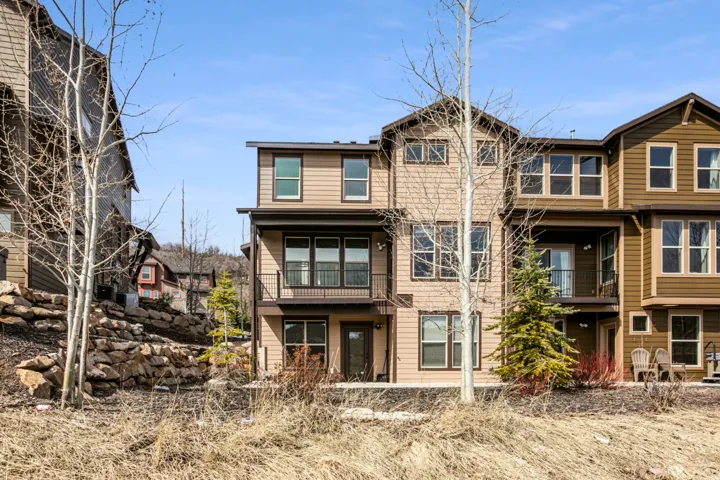 Multi-story townhome featuring a neutral-toned exterior with dark trim
