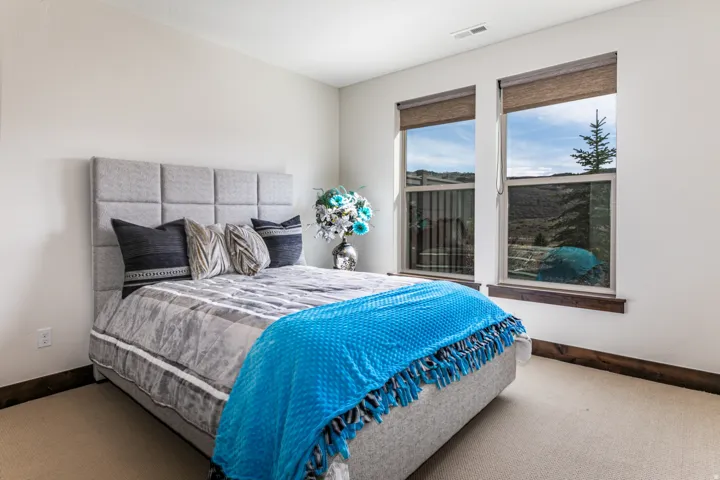 Bedroom featuring twin windows with natural light, neutral wall tones, and carpet flooring