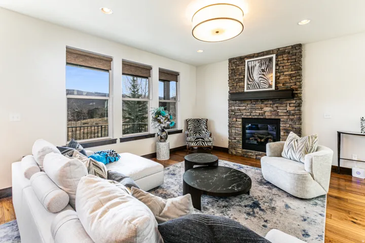 Living area featuring a stone-clad fireplace with a dark wood mantel, hardwood flooring, and recessed lighting