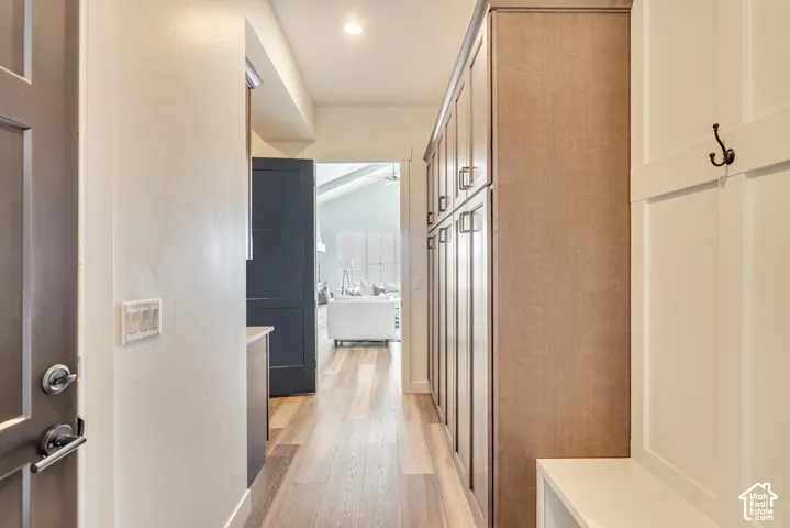 Hallway featuring extensive built-in cabinetry, wood-finish flooring, and paneling with a coat hook