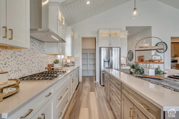 Modern kitchen featuring a vaulted shiplap ceiling, stainless steel appliances, a five-burner gas cooktop, white shaker cabinetry with gold-tone hardware, and wood-finish flooring