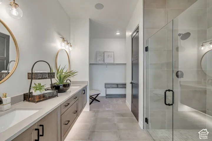 Bathroom featuring a dual vanity with light-toned countertops and wood-finish cabinetry, circular gold-framed mirrors, and contemporary lighting fixtures