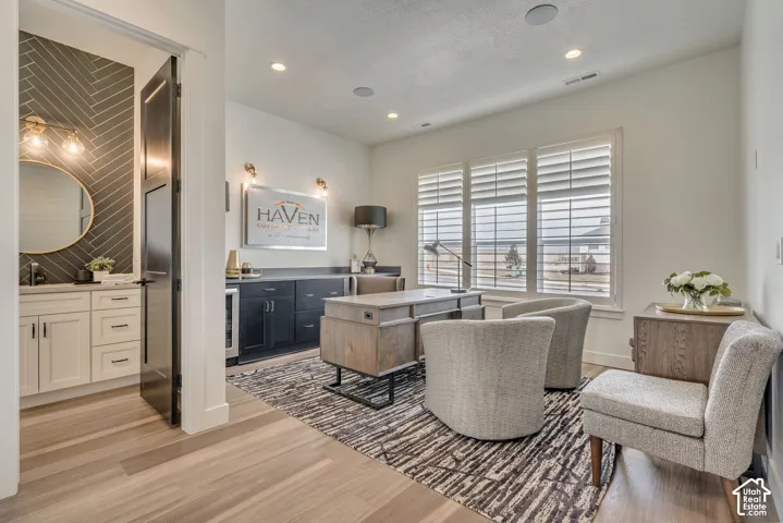 Bright interior space featuring light wood-finish flooring, recessed lighting, and large windows with privacy blinds
