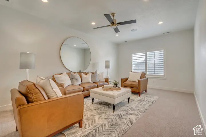 Bright living space featuring recessed lighting, a ceiling fan with a brass-finish fixture, and light-toned carpet flooring