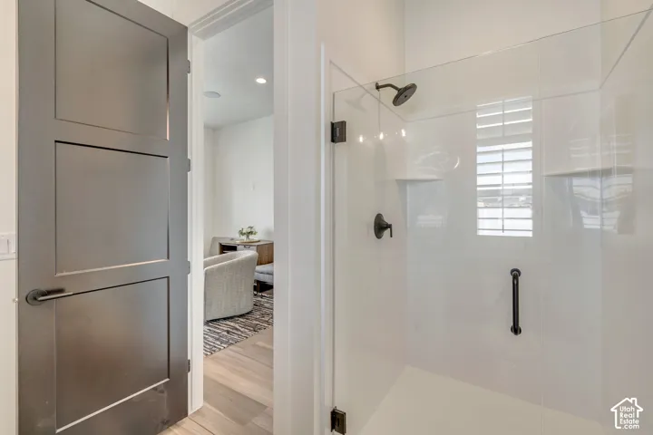 Frameless glass shower enclosure featuring a dark bronze showerhead, coordinating fixture, and grab bar