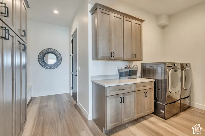Dedicated laundry area featuring wood-finish flooring, light wood cabinetry with dark hardware, and a light-colored countertop