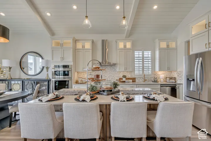 Gourmet kitchen featuring a large central island, white shaker cabinetry, stainless steel appliances, and a decorative tile backsplash