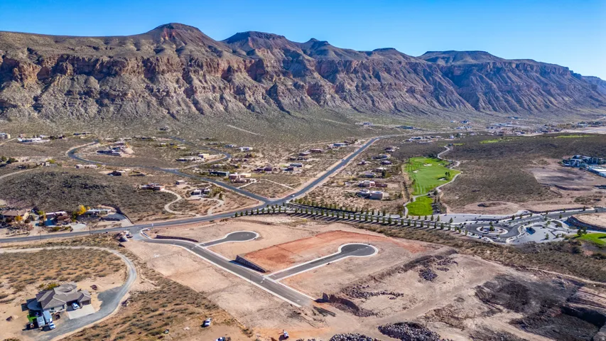 Expansive desert landscape featuring rugged mountain terrain, a paved road network, and multiple residential properties
