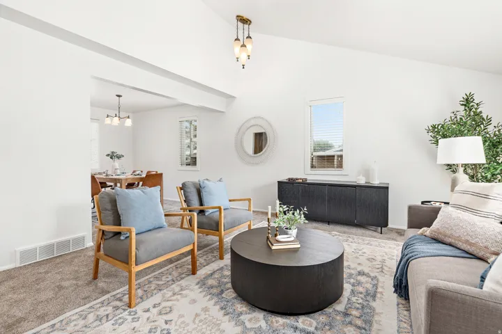 Vaulted ceiling with an overhead light fixture, carpeted flooring, and a large arched doorway