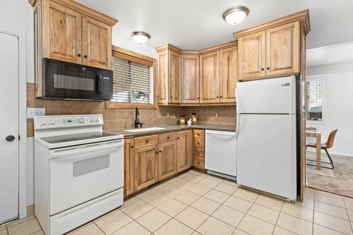 Kitchen featuring wood cabinetry, ceramic tile flooring, a tile backsplash, and a white electric range with a microwave above