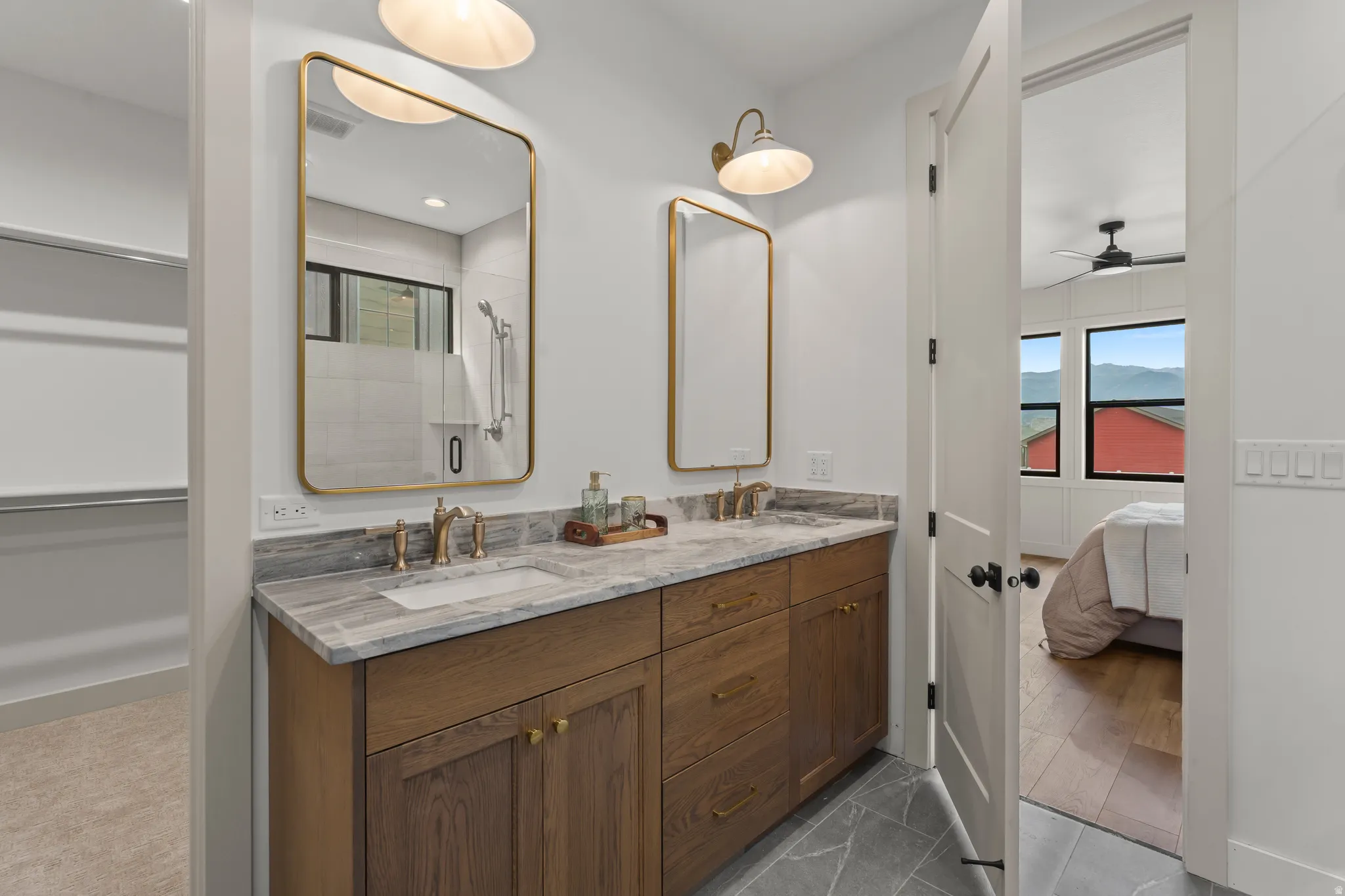 Double vanity with stone countertop, wood cabinetry, and gold-finish fixtures