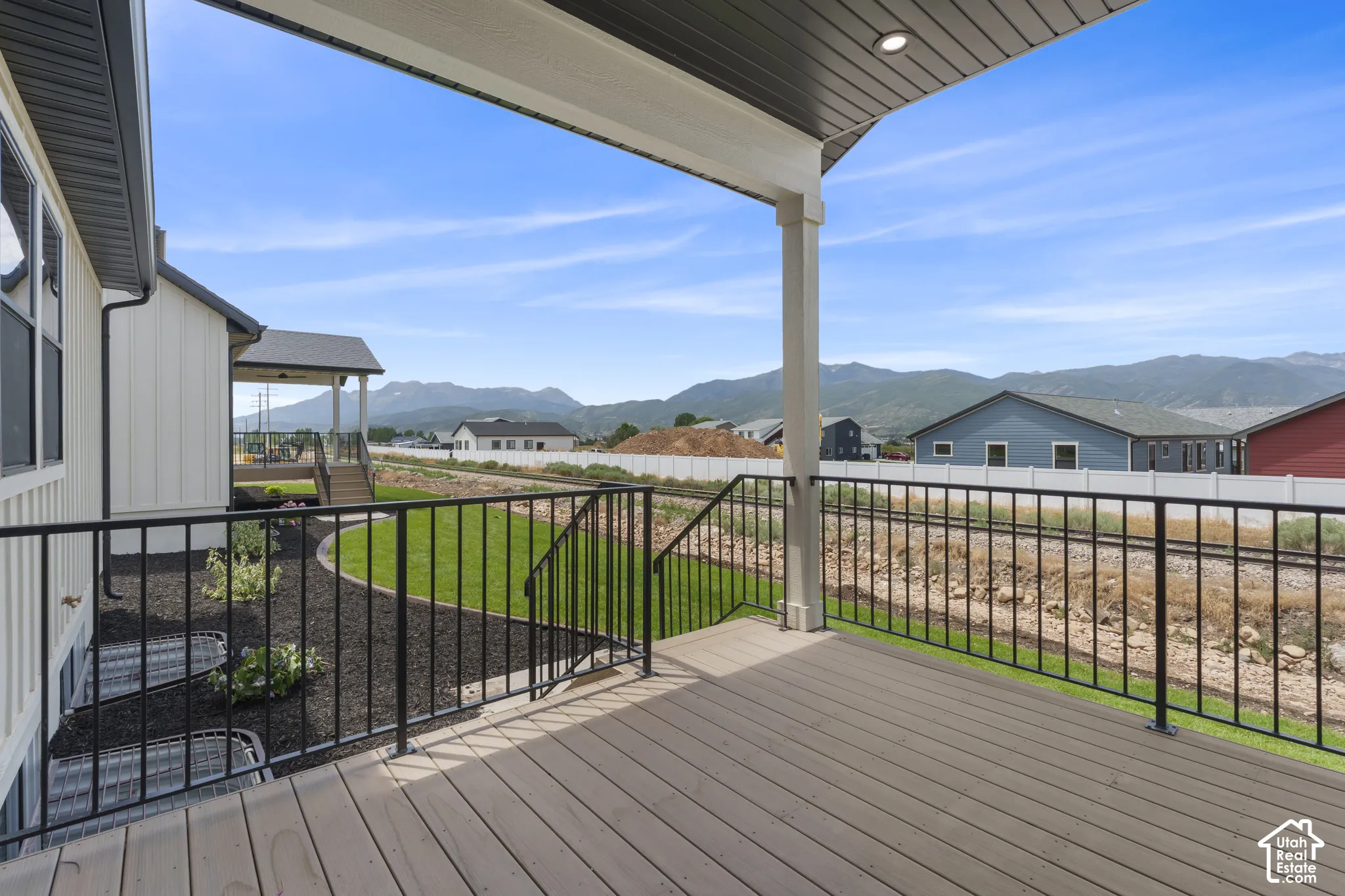 Spacious covered deck featuring composite decking and black metal railings