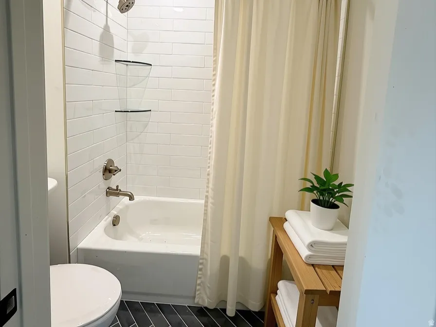Bathroom featuring a white subway tile surround, recessed lighting, chrome shower fixtures, and dark herringbone floor tiling