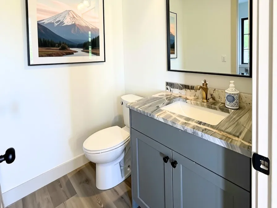 Bathroom featuring a grey vanity with a rectangular undermount sink, a patterned stone countertop, and a wall-mounted light fixture