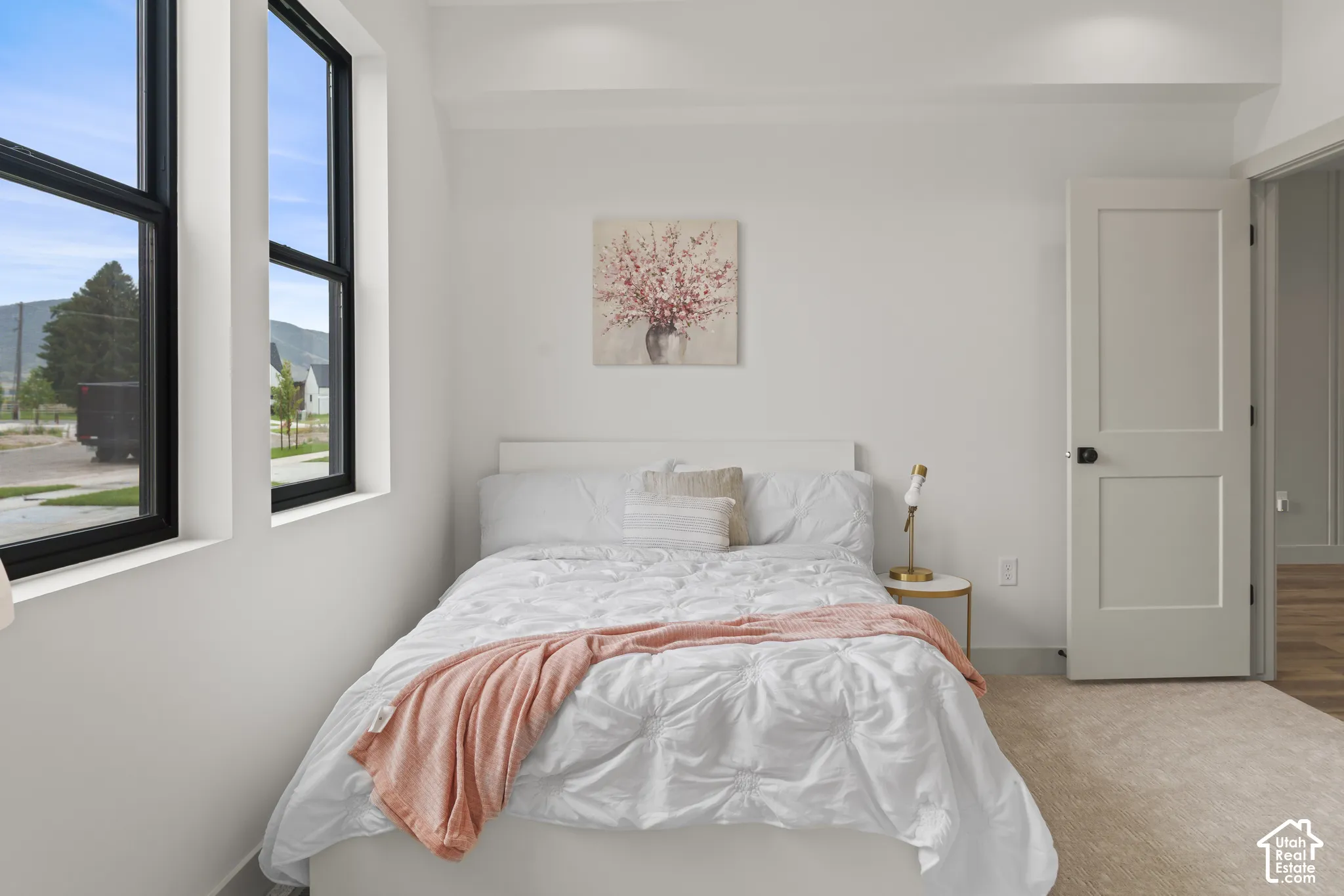 Bright interior featuring two large black-framed windows, white walls, recessed ceiling lighting, and a neutral-toned carpet