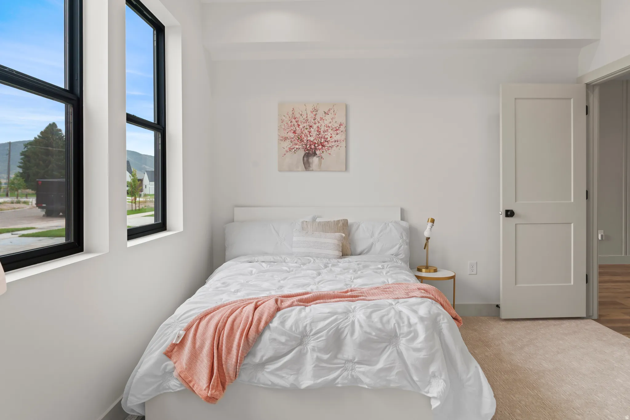 Bright interior featuring two large black-framed windows, white walls, recessed ceiling lighting, and a neutral-toned carpet