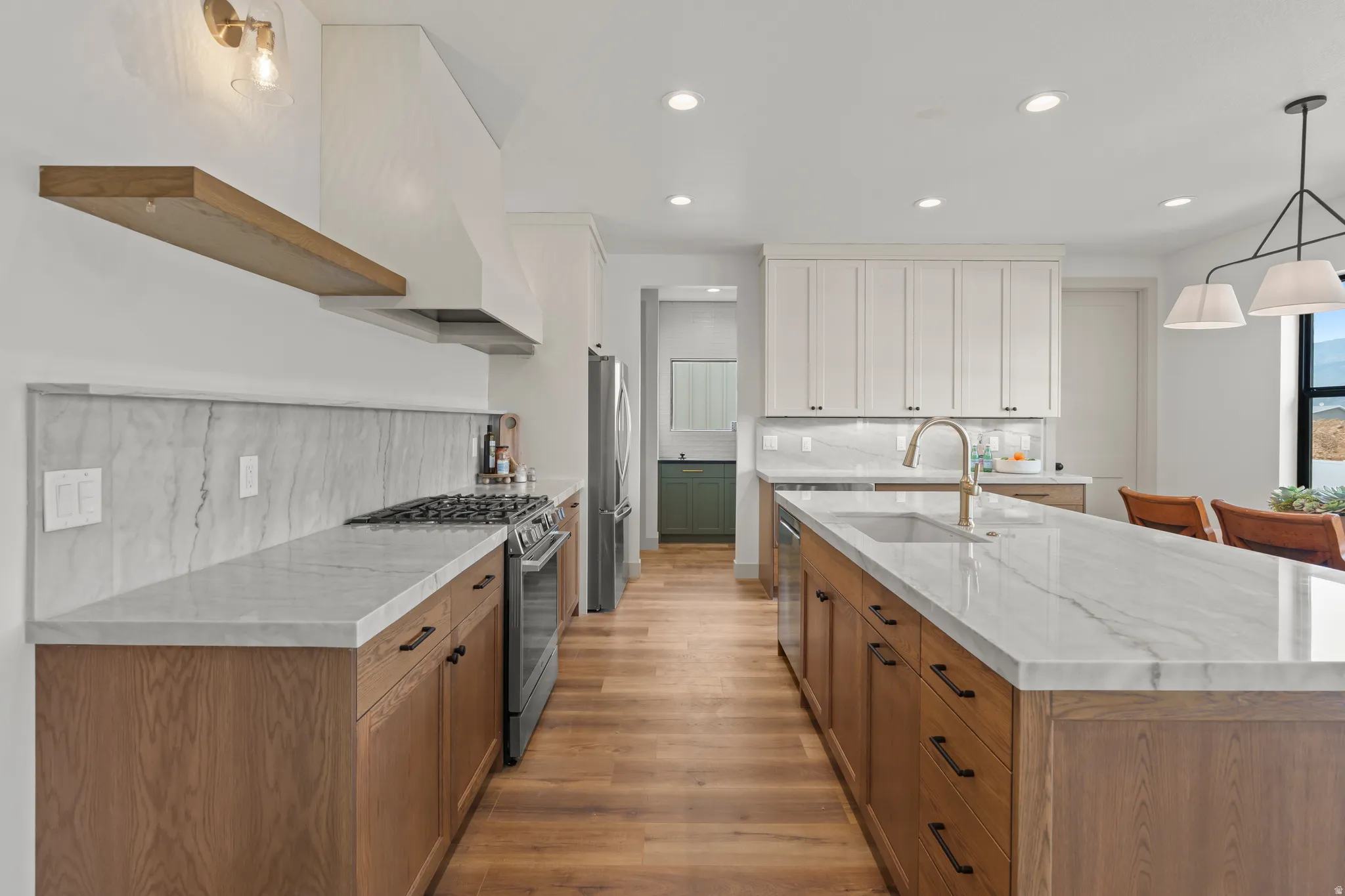 Gourmet kitchen with wood-finish flooring, a substantial center island with integrated sink, stone countertops, and a full-height stone backsplash