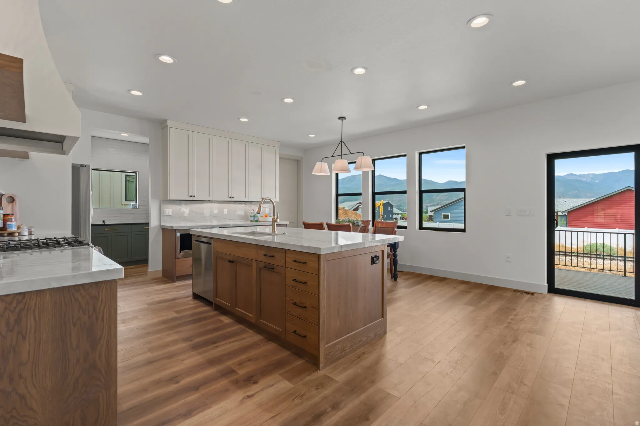 Gourmet kitchen with an expansive island, white shaker cabinetry, and wood-finish flooring