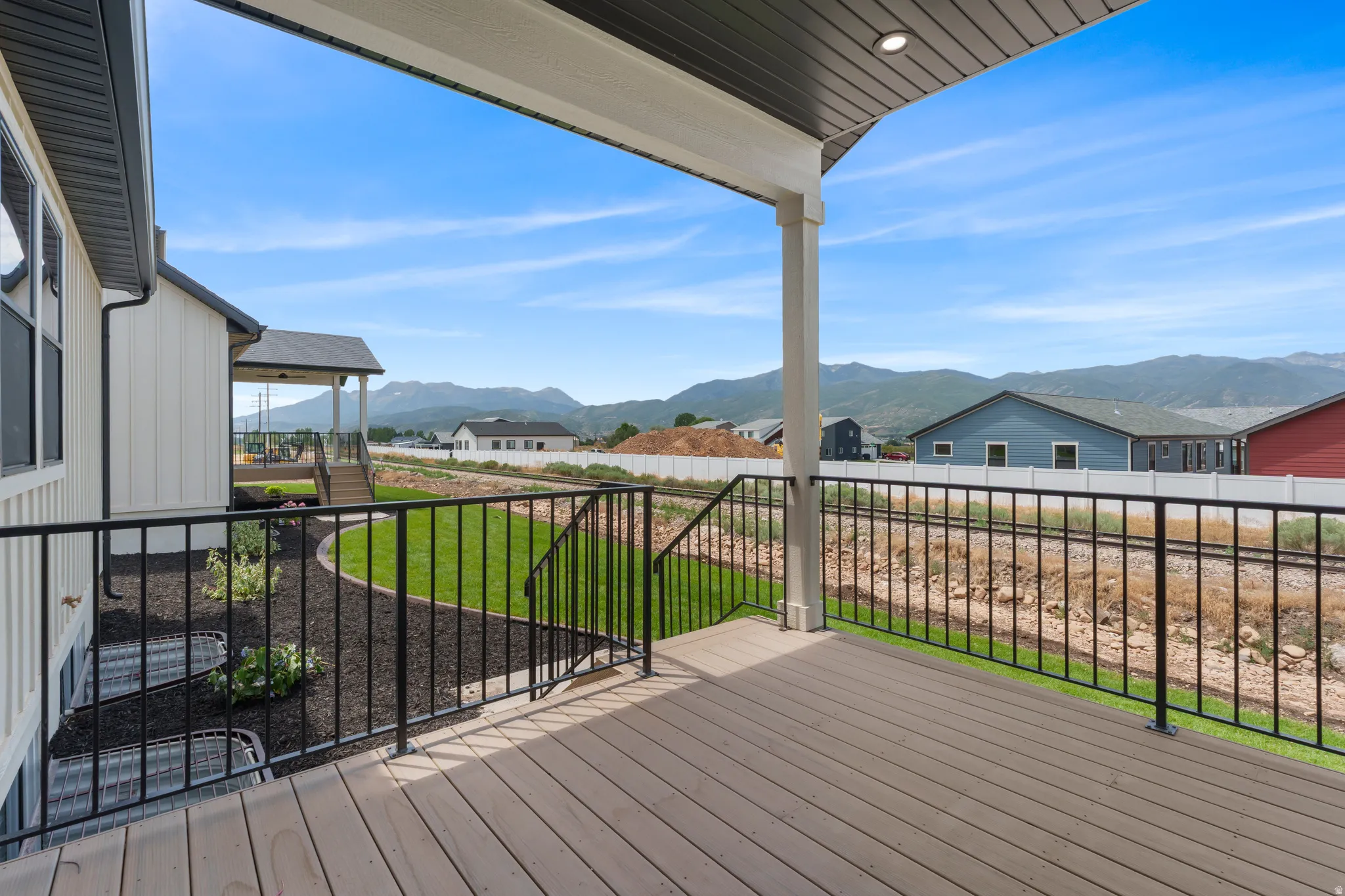 Spacious covered deck featuring composite decking and black metal railings