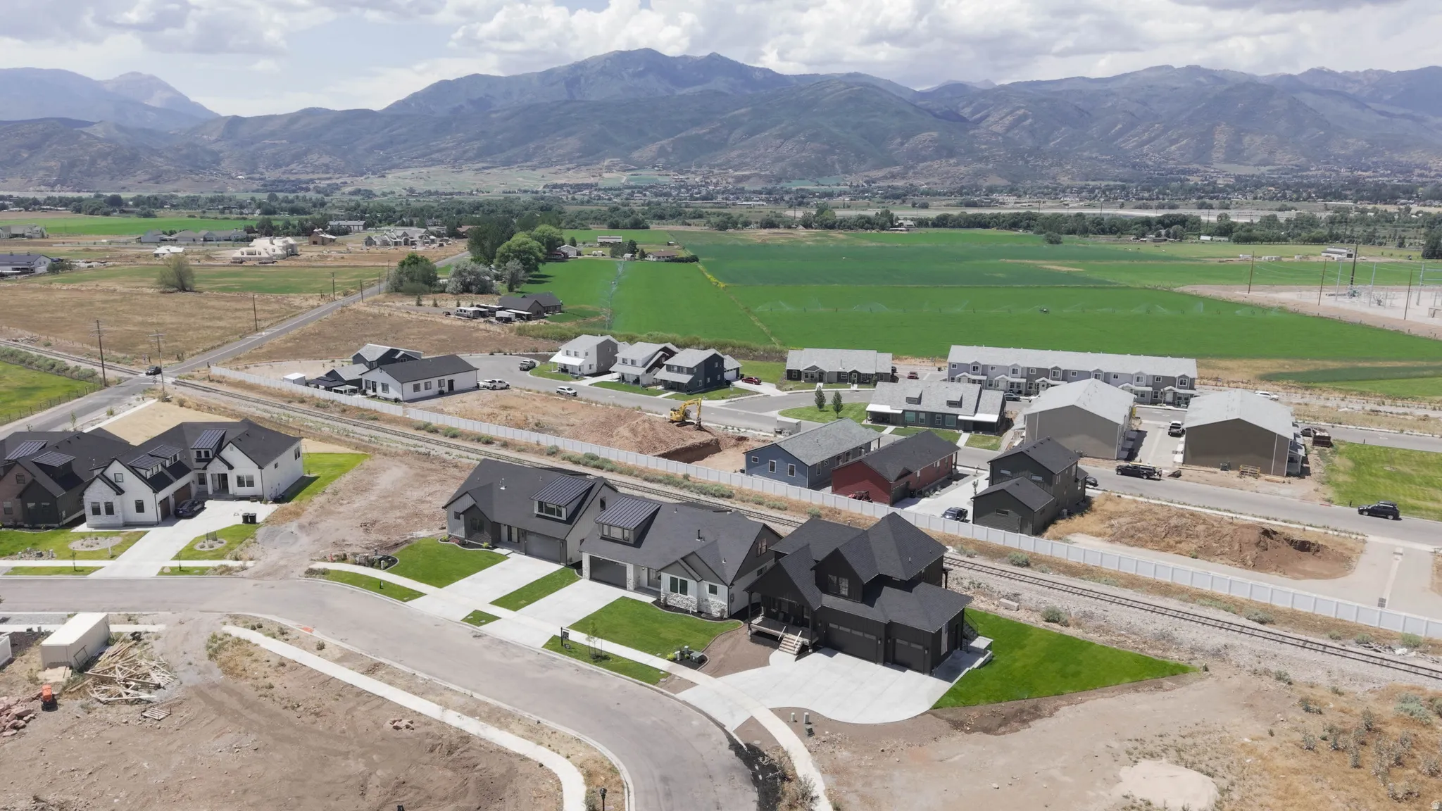 Aerial perspective showcasing a developing residential area with modern homes and mountain scenery