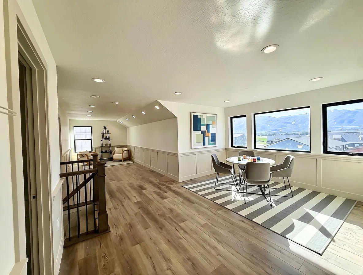 Expansive loft area featuring wood-finish flooring, recessed lighting, wainscoting, and large windows with mountain scenery