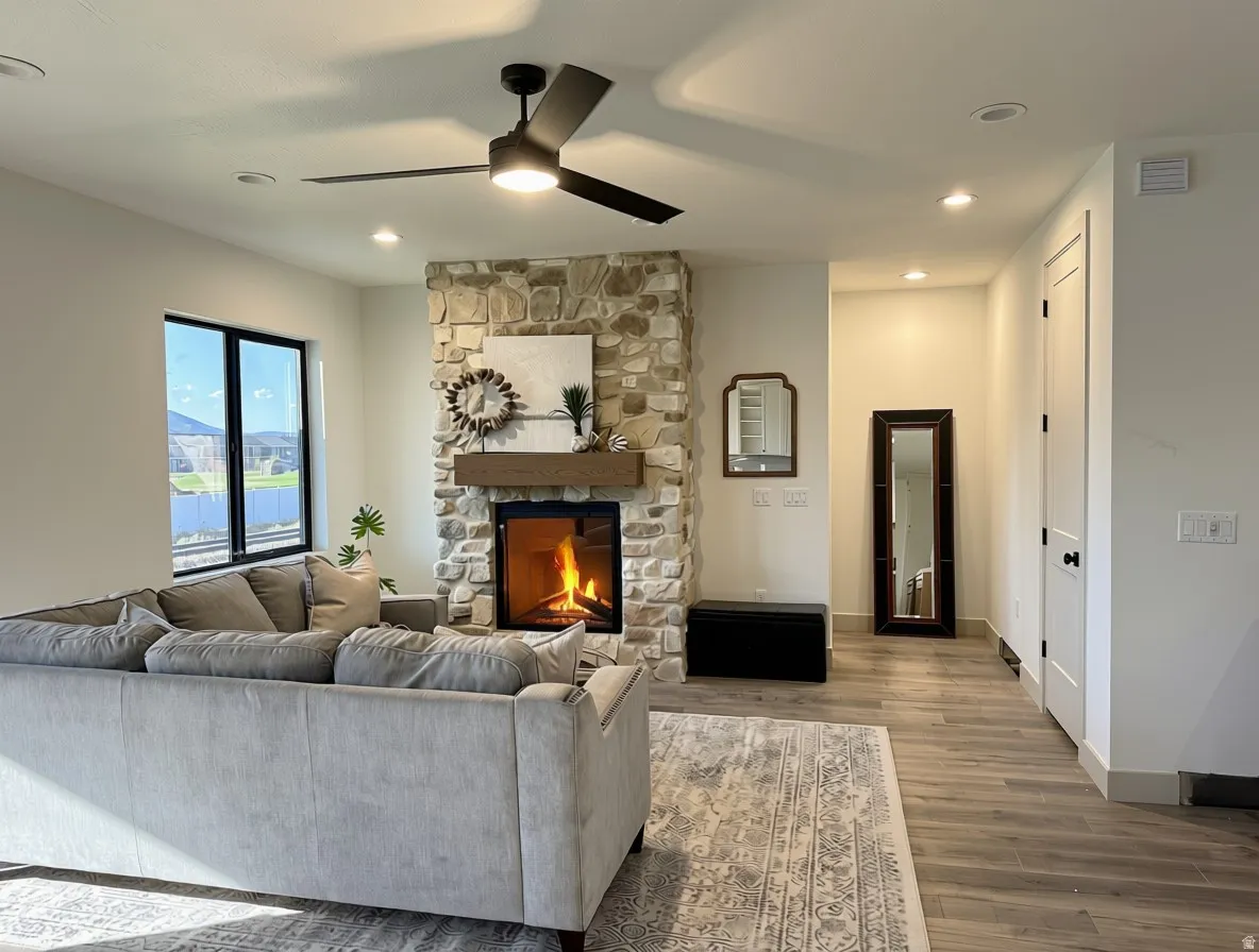 Living area featuring a floor-to-ceiling stone fireplace with a wood mantel, black-framed windows, and wood-finish flooring