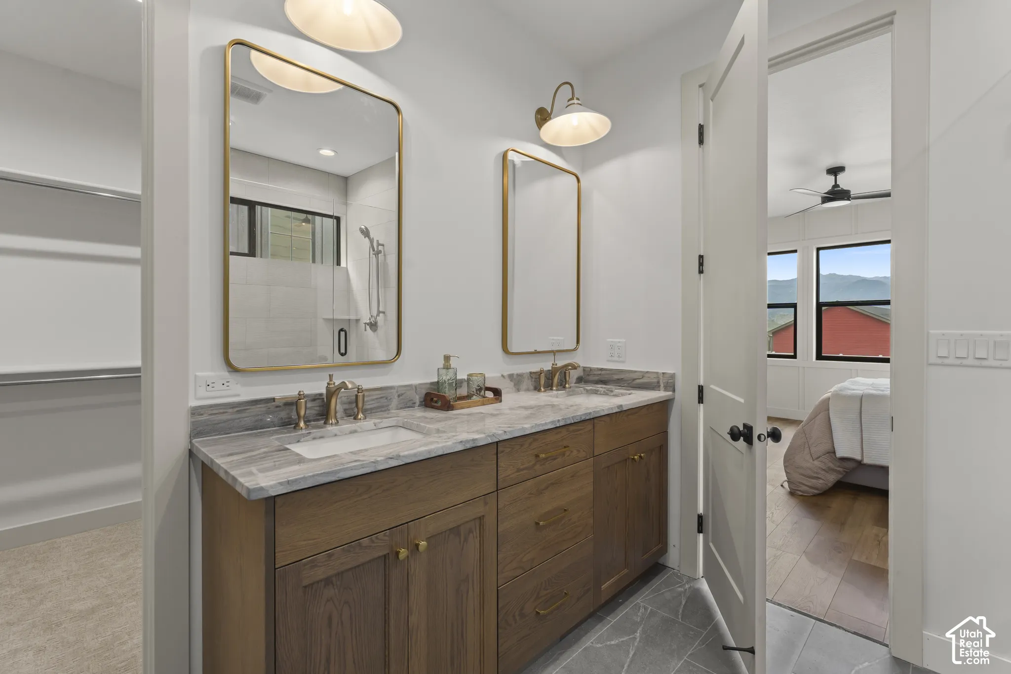Double vanity with stone countertop, wood cabinetry, and gold-finish fixtures