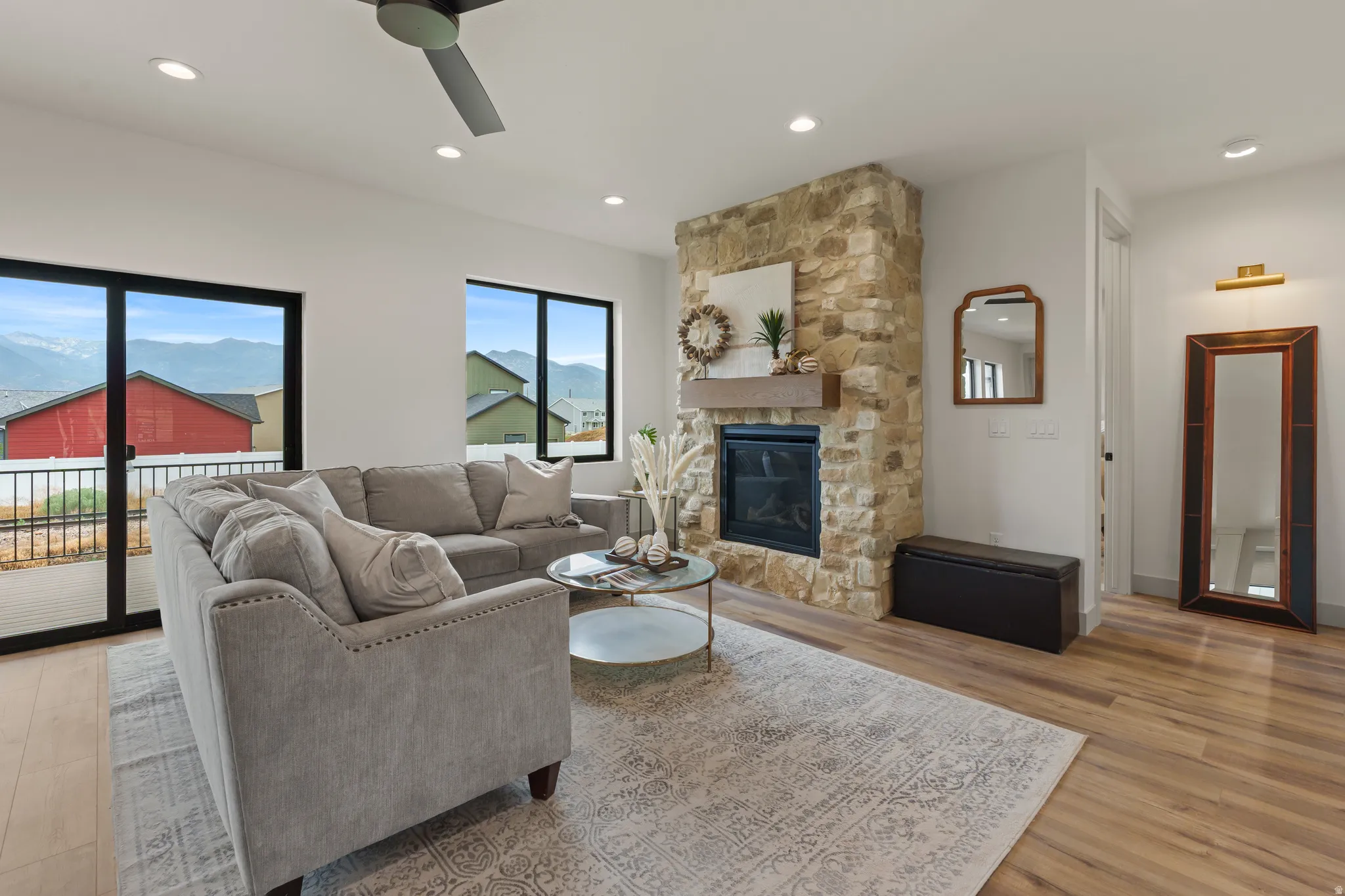 Spacious living area featuring a stone fireplace with a wood mantle, recessed lighting, and a ceiling fan