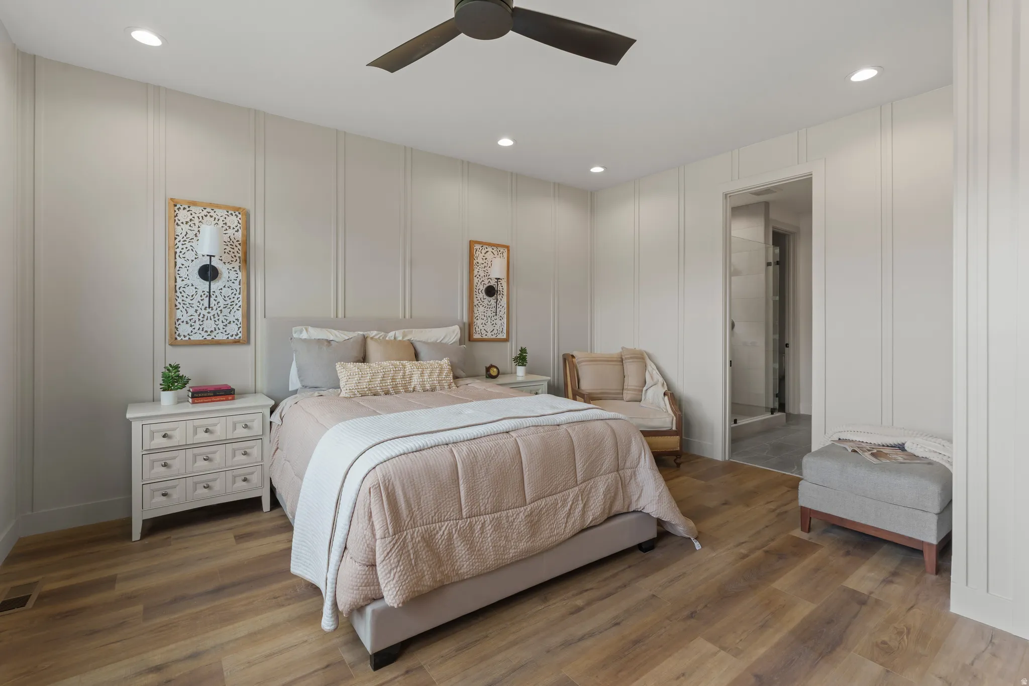 Bedroom featuring wood-finish flooring, recessed lighting, a ceiling fan, vertical panel accent walls, and an attached bathroom with a glass-enclosed shower