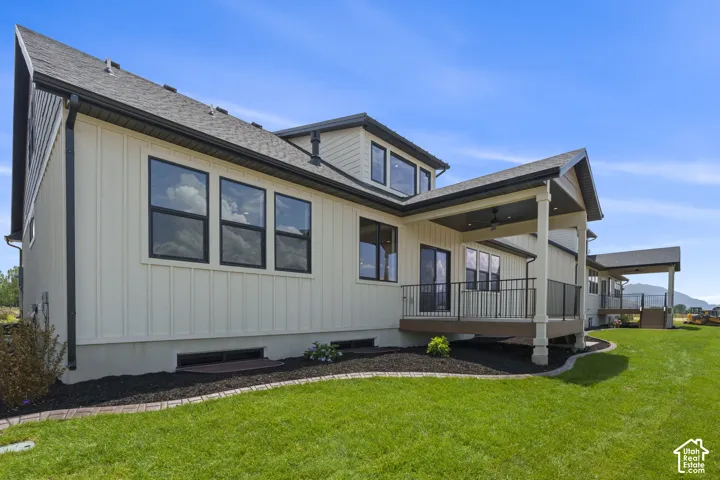 Exterior showcasing light-colored vertical siding, dark-framed windows, and a covered patio with dark railings