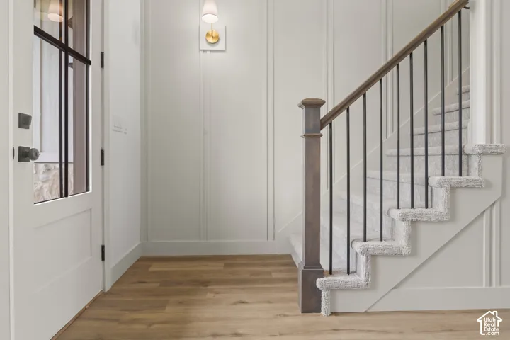 Staircase featuring wood newel post and handrail with black iron balusters, complemented by light grey carpeted treads