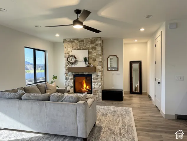 Living area featuring a floor-to-ceiling stone fireplace with a wood mantel, black-framed windows, and wood-finish flooring