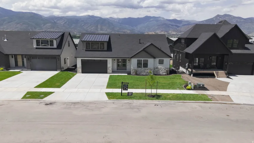Modern farmhouse exterior featuring a dark gray roof, light gray siding, and stone accents