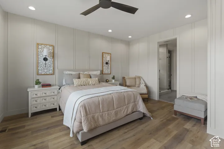 Bedroom featuring wood-finish flooring, recessed lighting, a ceiling fan, vertical panel accent walls, and an attached bathroom with a glass-enclosed shower