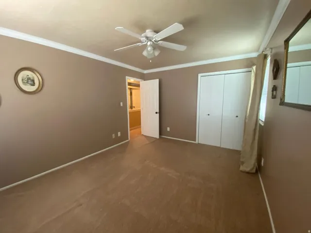 3rd bedroom  featuring a ceiling fan with light kit, crown molding, white baseboards, and a white bi-fold closet