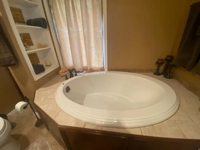 Built-in soaking tub with tile surround and dark wood cabinetry