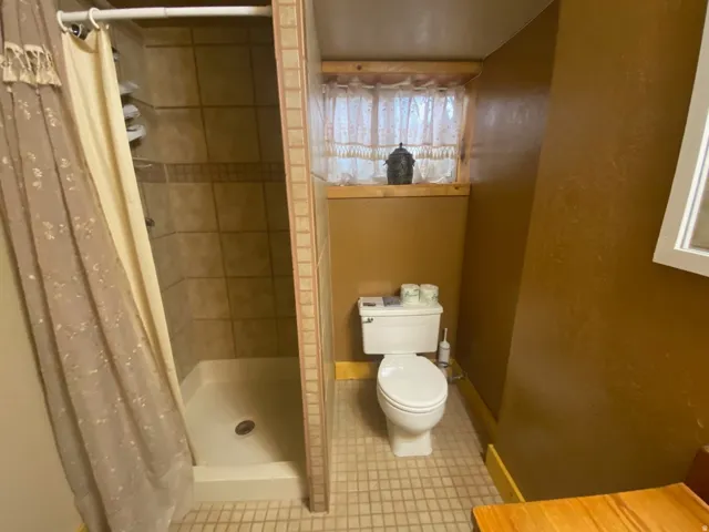 Tiled shower enclosure with built-in shelving, glass tile accent band, and a white shower base