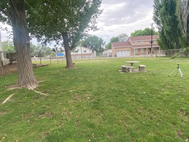 Expansive green lawn featuring mature trees and a stone picnic set