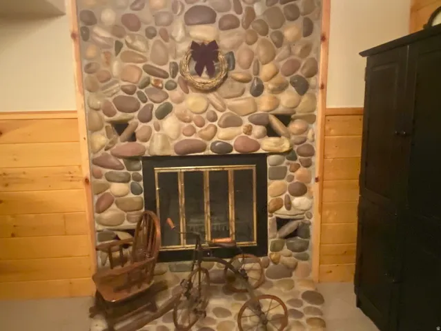River rock fireplace with a black metal screen and an integrated hearth