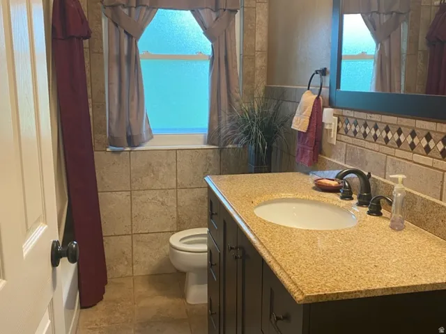 Well-appointed bathroom featuring a dark wood-finish vanity with an undermount sink, a speckled countertop, and oil-rubbed bronze fixtures.  Full Bathroom located in the hallway.