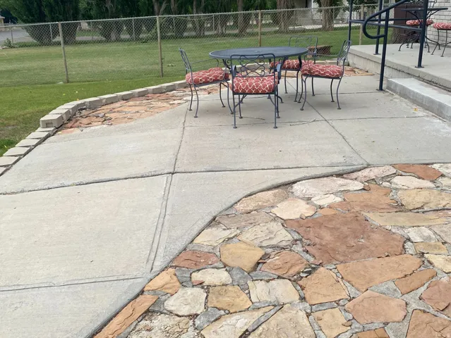 Concrete patio with flagstone accents and a grass lawn located in the front of the home.