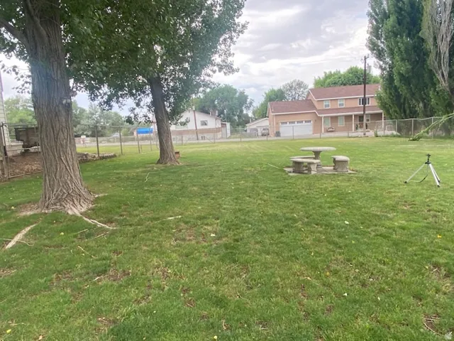 Expansive green lawn featuring mature trees and a stone picnic set