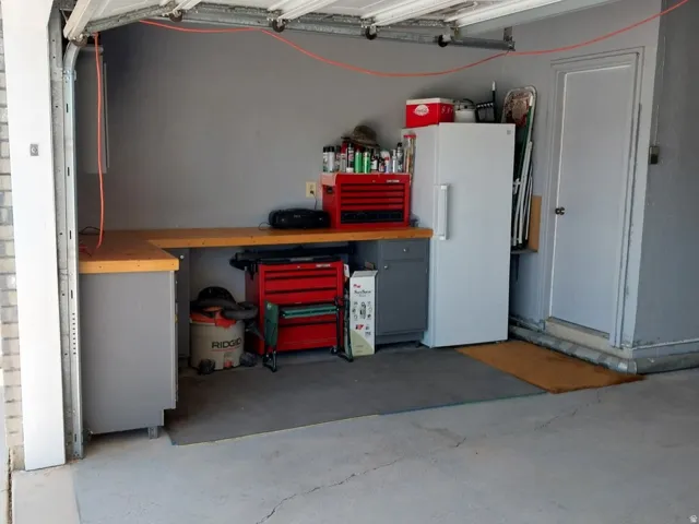 Garage interior featuring a sectional workbench with light wood-finish countertops and grey base cabinetry