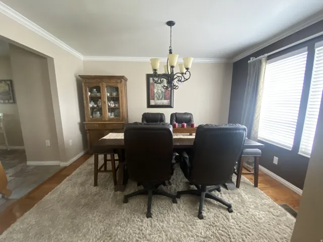 Formal dining area featuring a dark wood-finish dining table, crown molding, and a traditional chandelier