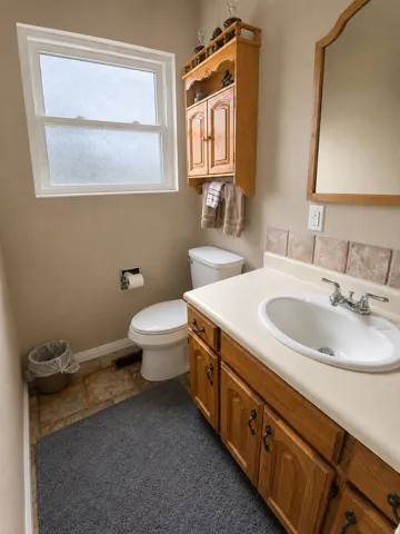 Bathroom featuring a vanity with wood cabinetry, an integrated sink, and a light-toned countertop