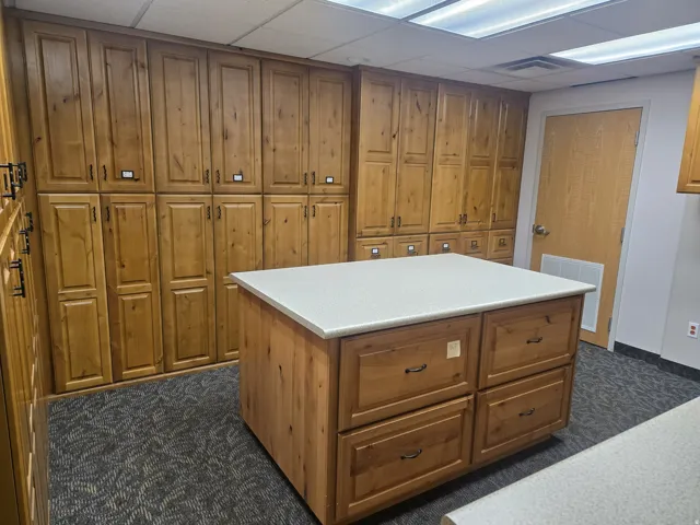 Central island with a light-toned solid surface countertop and wood-finish cabinetry