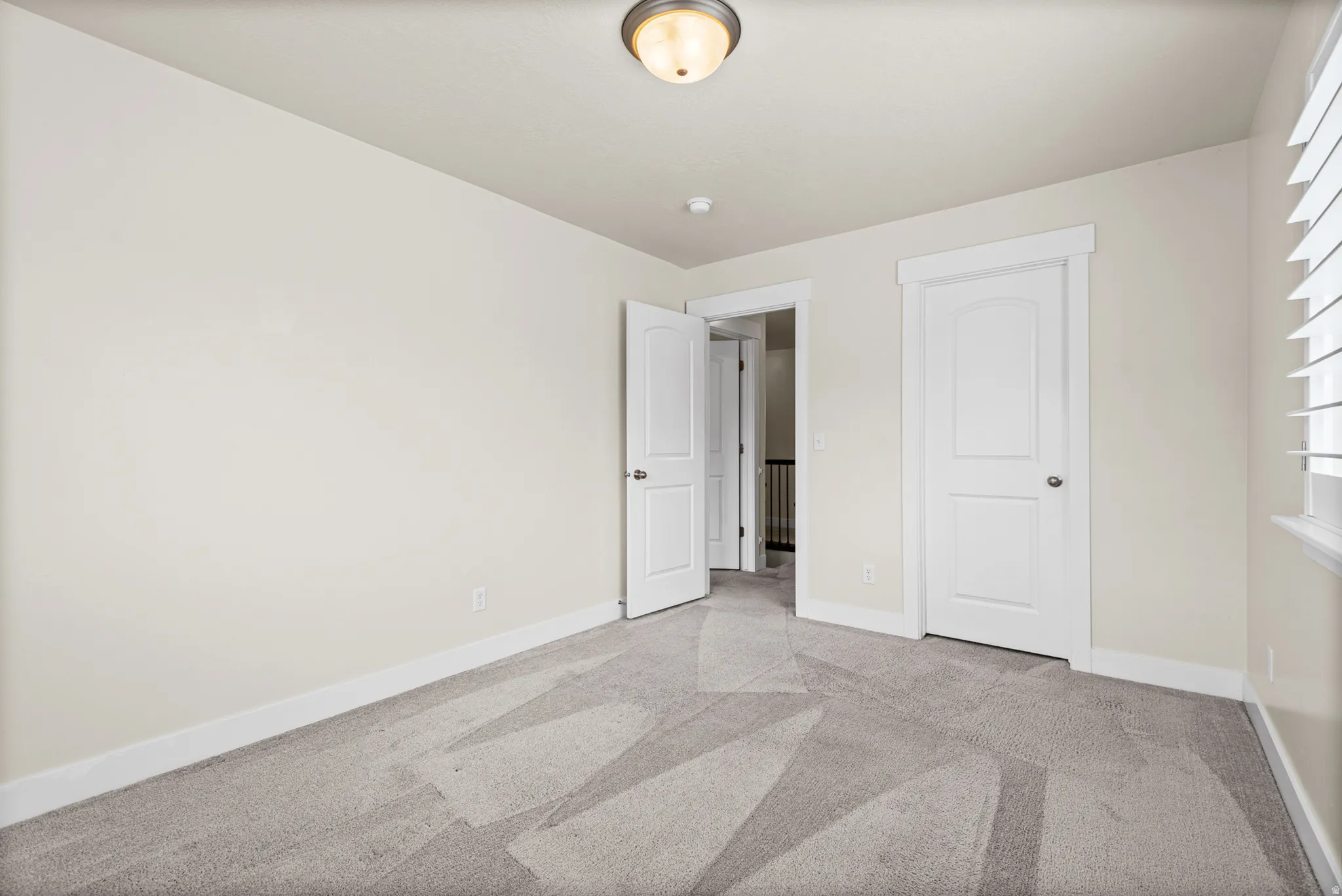 Neutral tone walls with white trim and grey patterned carpeting