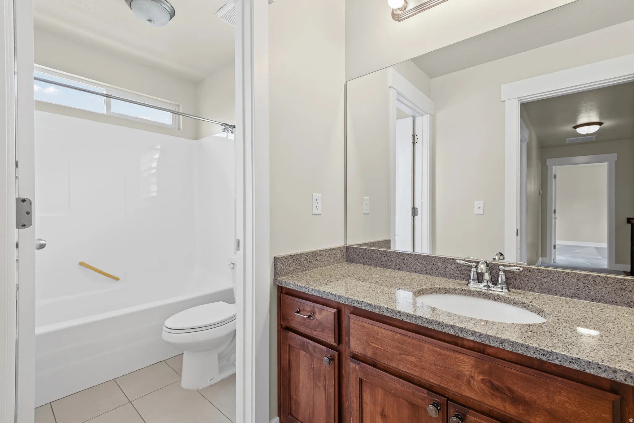 Bathroom featuring a wood vanity with a stone countertop, an undermount sink, and a large mirror