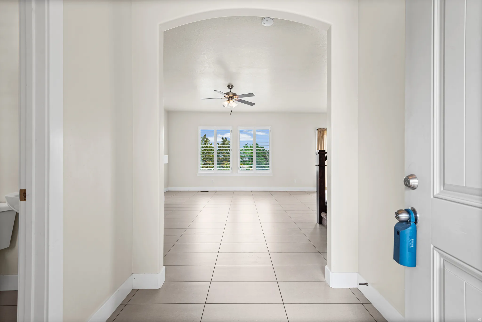 Entryway featuring a wide archway opening into a room with light tile flooring, high ceilings, and a ceiling fan